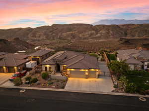View of front of home featuring an attached garage, concrete driveway, a mountain view, and a tiled roof