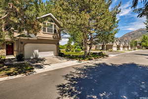 View of front of house with stucco siding, stone siding, driveway, a residential view, and an attached garage