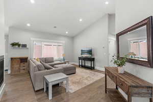 Living area with high vaulted ceiling, light wood-style flooring, healthy amount of natural light, and recessed lighting