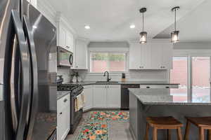 Kitchen with freestanding refrigerator, black gas range, dark stone counters, white cabinetry, and a textured ceiling