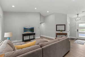 Living area featuring recessed lighting, wood finished floors, high vaulted ceiling, and a chandelier