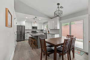 Dining room featuring lofted ceiling, light wood-style flooring, recessed lighting, and a textured ceiling