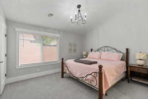 Bedroom with carpet, a textured ceiling, and a chandelier