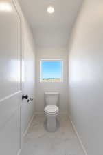 Bathroom featuring light marble finish floors and toilet