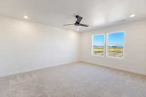 Empty room featuring light carpet, ceiling fan, and recessed lighting