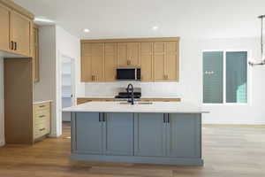 Kitchen with tasteful backsplash, light stone countertops, appliances with stainless steel finishes, recessed lighting, and light wood-style floors