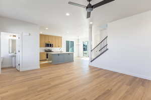 Unfurnished living room featuring stairs, recessed lighting, light wood finished floors, a chandelier, and a ceiling fan