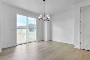 Unfurnished dining area featuring a chandelier and light wood-type flooring