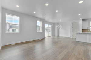 Unfurnished living room with recessed lighting, light wood finished floors, a chandelier, and a textured ceiling
