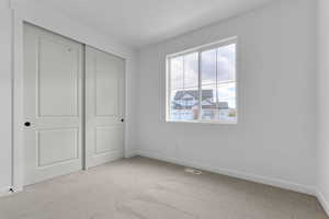 Unfurnished bedroom with light colored carpet and a closet
