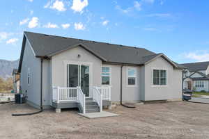 Back of house with stucco siding and roof with shingles