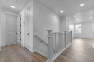 Hallway featuring an upstairs landing, recessed lighting, and light wood-style floors
