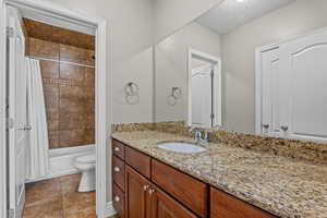 Full bath featuring vanity, shower / tub combo, and dark tile patterned flooring