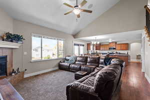 Living room featuring a tiled fireplace, high vaulted ceiling, arched walkways, a chandelier, and a ceiling fan