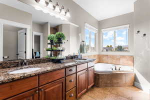 Bathroom with double vanity, a bath, and light tile patterned floors