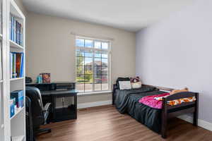 Bedroom featuring wood finished floors and an office area