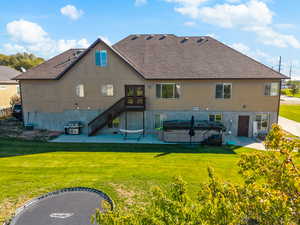 Rear view of house with a patio, a lawn, a hot tub, and stucco siding