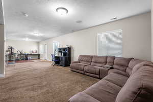 Living room featuring a textured ceiling, carpet floors, and an office area