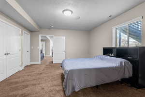 Carpeted bedroom with a textured ceiling and a closet