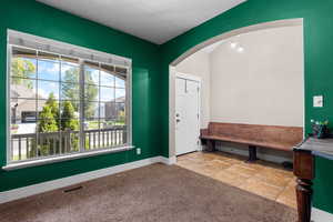 Foyer entrance featuring light carpet, arched walkways, and light tile patterned floors