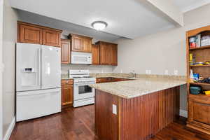 Kitchen featuring white appliances, a peninsula, light stone countertops, brown cabinets, and dark wood-style floors