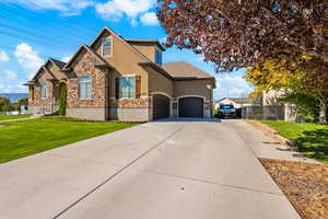 View of front of house with stucco siding, stone siding, concrete driveway, and an attached garage