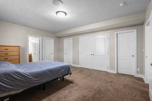 Bedroom with carpet flooring, a textured ceiling, two closets, and connected bathroom