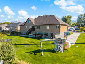 Rear view of house featuring a lawn, a playground, a mountain view, stucco siding, and a residential view