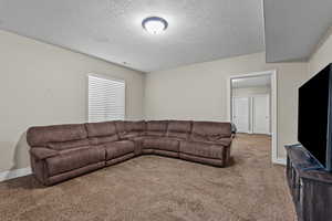 Living area featuring carpet flooring and a textured ceiling
