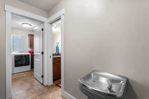 Washroom with light tile patterned floors and independent washer and dryer