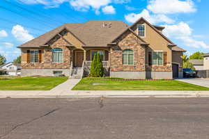 Craftsman house with stone siding, a front yard, stucco siding, and a garage