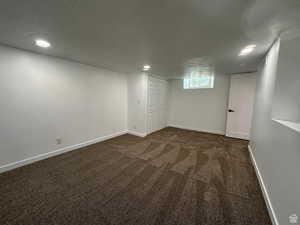 Basement featuring dark carpet, a textured ceiling, and recessed lighting