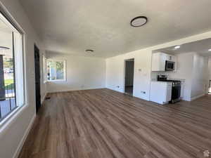 Unfurnished living room featuring dark wood-type flooring and a textured ceiling