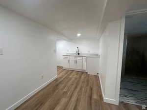 Bar area with white cabinets, light wood-style flooring, and a textured ceiling