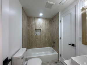 Full bath featuring a textured ceiling and bathtub / shower combination