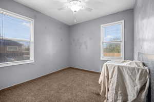 Carpeted bedroom featuring ceiling fan and baseboards