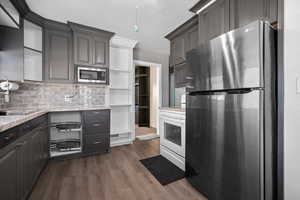 Kitchen with stainless steel appliances, LVP wood-style floors, decorative backsplash, gray cabinets