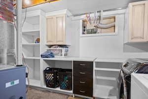Laundry room featuring washer and dryer, cabinet space, and heating unit