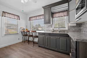 Kitchen featuring stainless steel microwave, light countertops, decorative backsplash, and LVP flooring