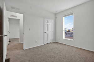 Unfurnished bedroom featuring light carpet and baseboards