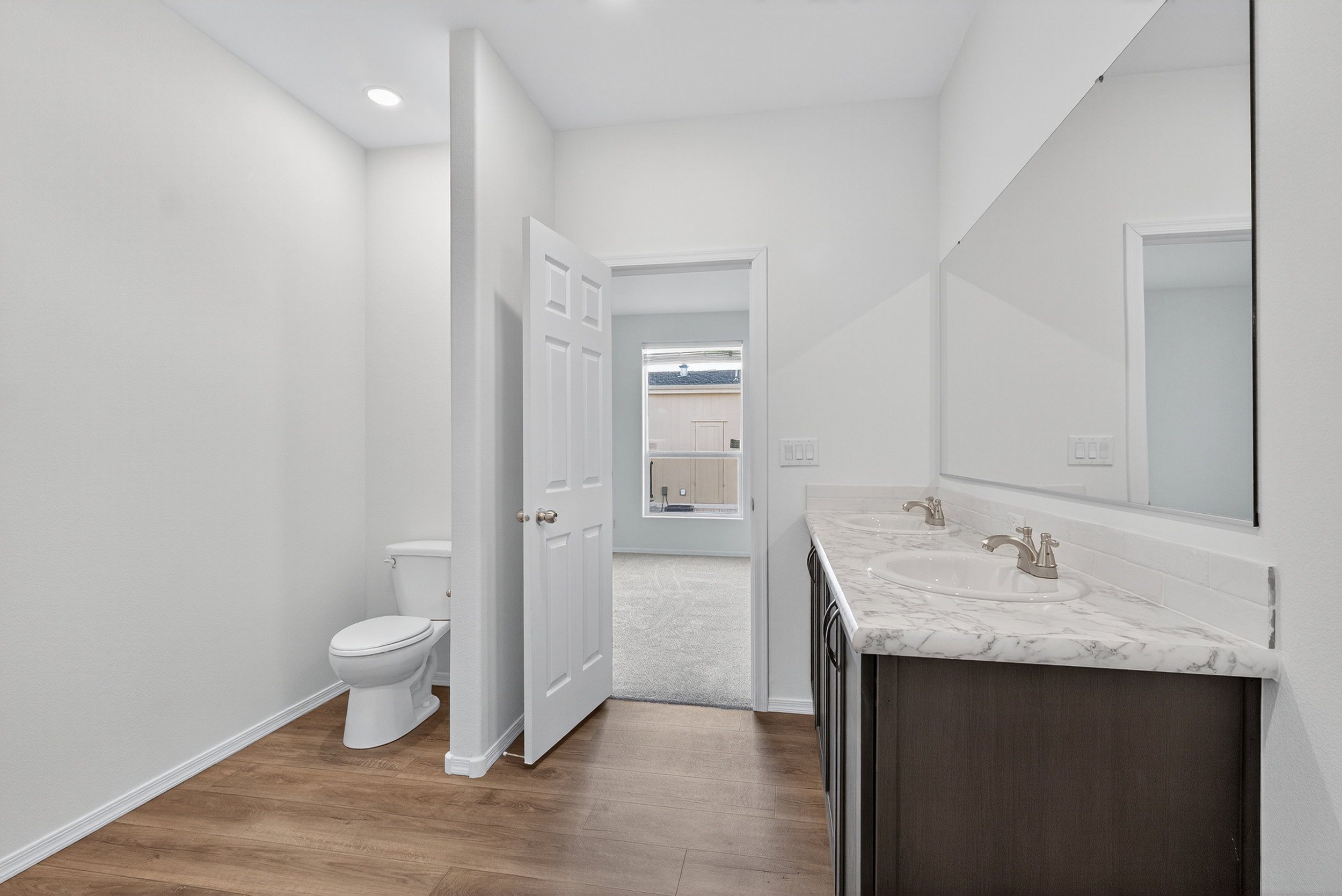 Bathroom with double vanity and dark wood-style floors