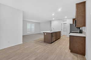 Kitchen with open floor plan, recessed lighting, an island with sink, light wood-type flooring, and stainless steel appliances