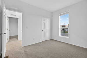 Unfurnished bedroom featuring light colored carpet and baseboards