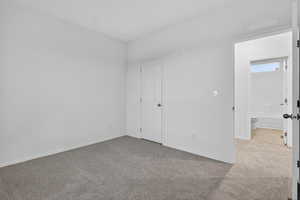 Unfurnished bedroom with light carpet and baseboards