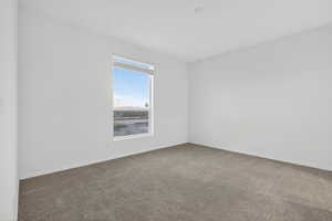 Carpeted spare room featuring baseboards