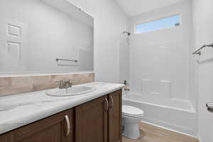Bathroom featuring washtub / shower combination, vanity, light wood-type flooring, and decorative backsplash