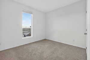 Carpeted spare room featuring baseboards