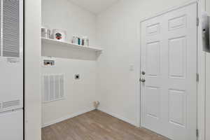 Washroom featuring a heating unit, light wood-style flooring, hookup for a washing machine, and electric dryer hookup
