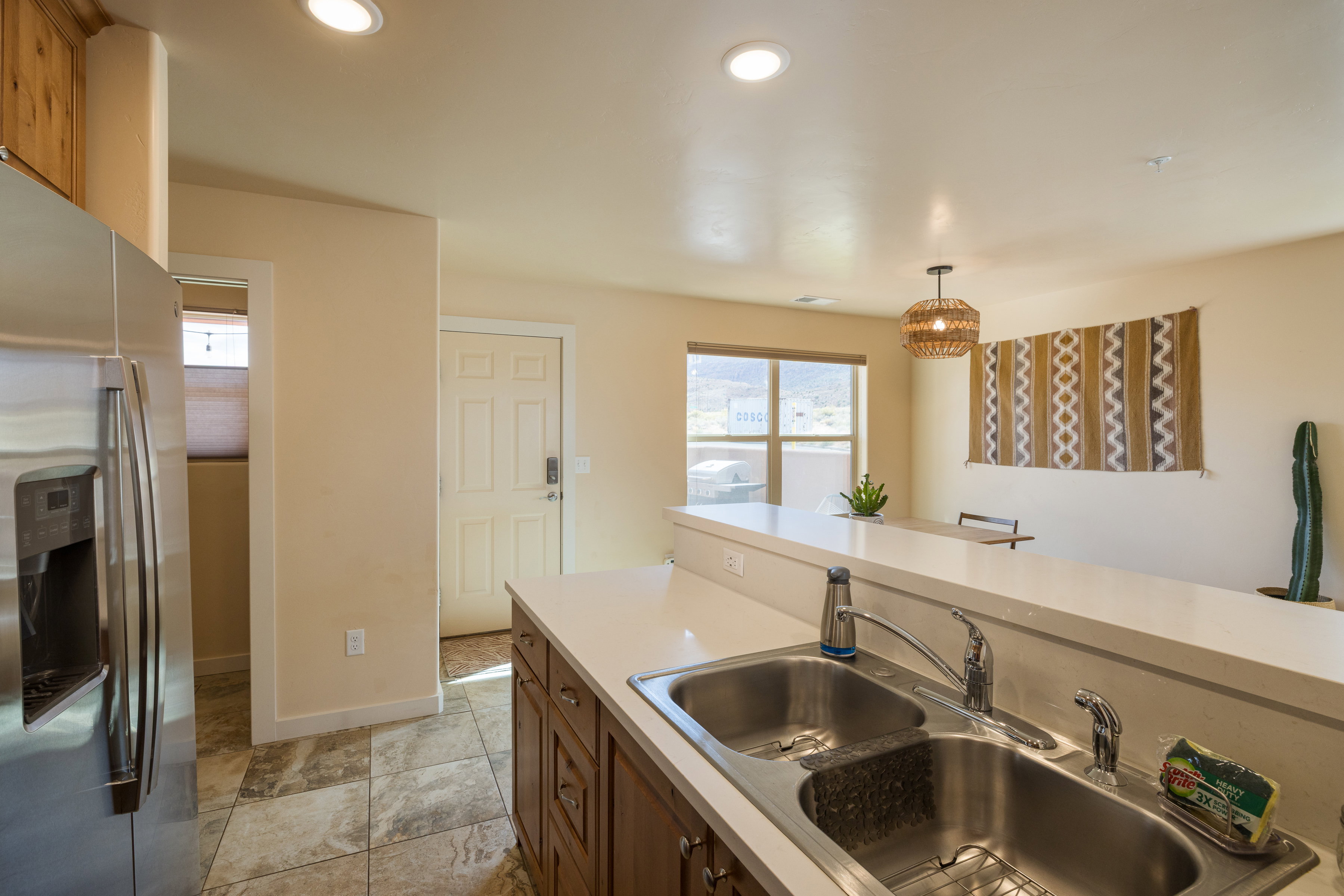 Kitchen with stainless steel fridge with ice dispenser, light countertops, healthy amount of natural light, hanging light fixtures, and recessed lighting