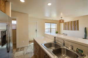 Kitchen with stainless steel fridge with ice dispenser, light countertops, healthy amount of natural light, hanging light fixtures, and recessed lighting